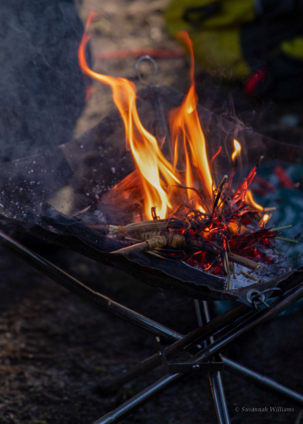 A straw doll burning in a fire basket, flames rising through the rushes.