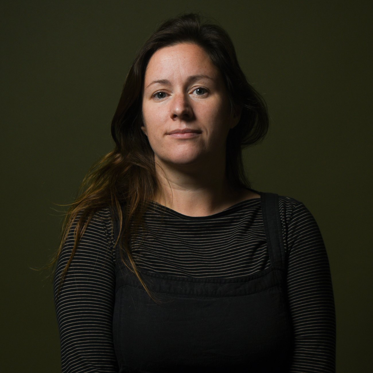Susannah Williams, photographer, against a dark green backdrop.