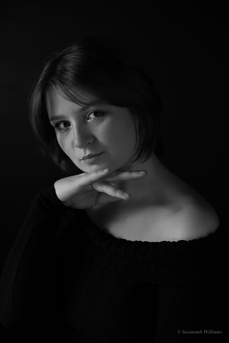 A black and white portrait of a young woman with a short bob, her chin resting on her hand.