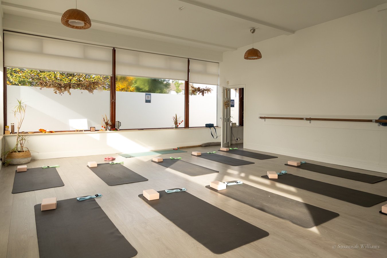 The empty studio before the class, mats and blocks laid out in rows in the morning light.