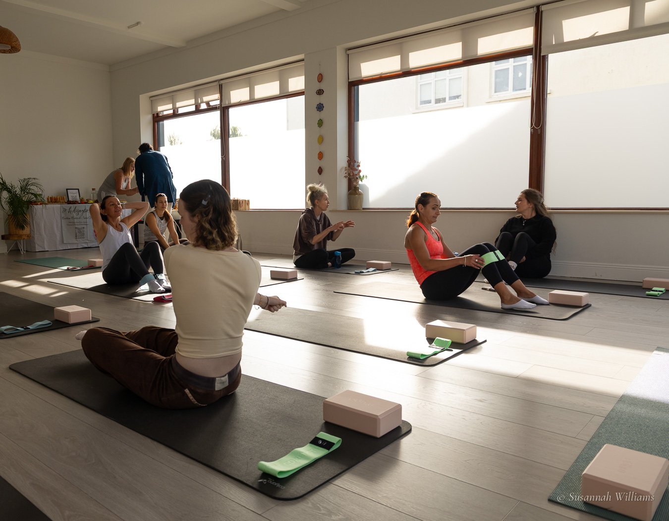 Women sitting on their mats chatting in the low sun before the class begins.