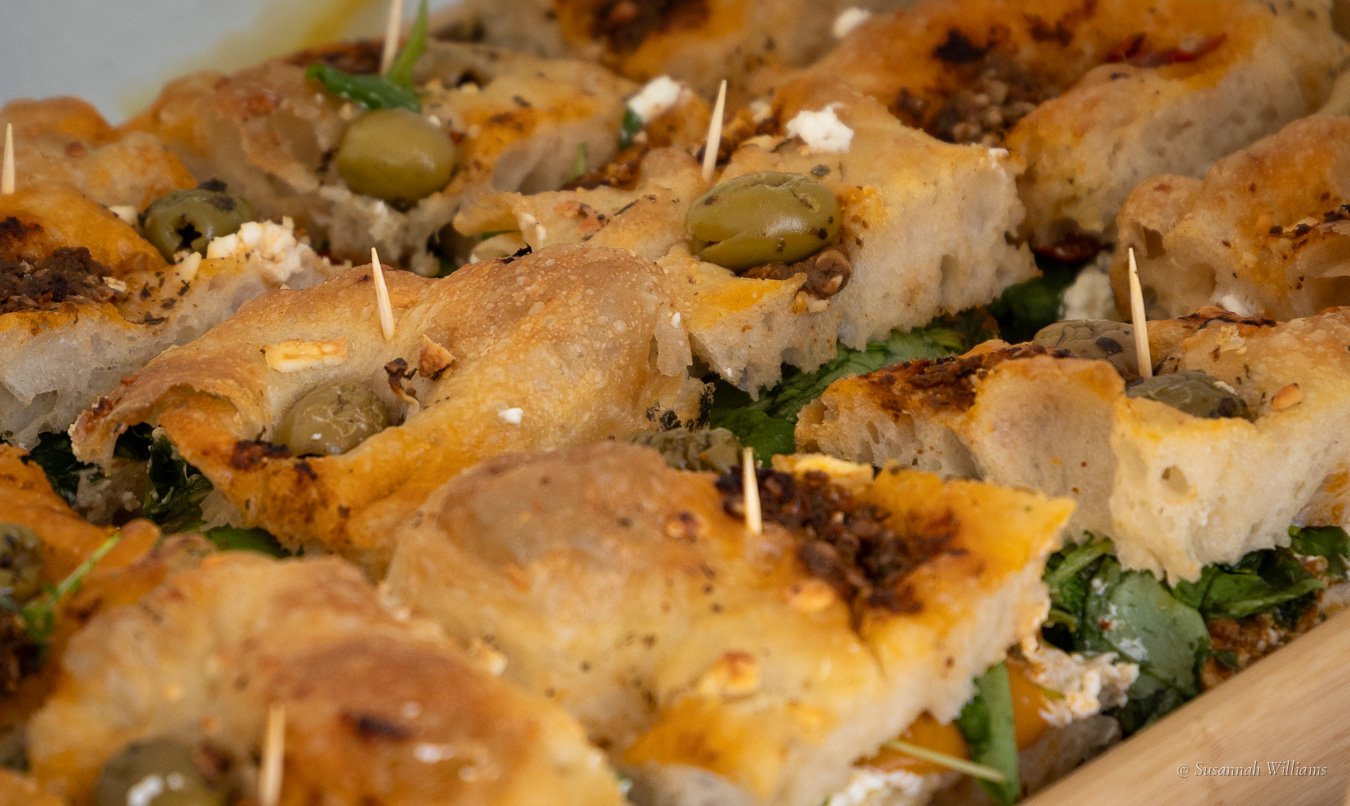 Focaccia sandwiches filled with fresh greens, golden and crisp on top.